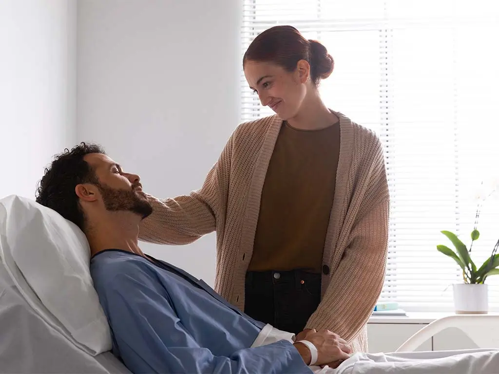 Woman supporting a sick loved one while he rests in bed