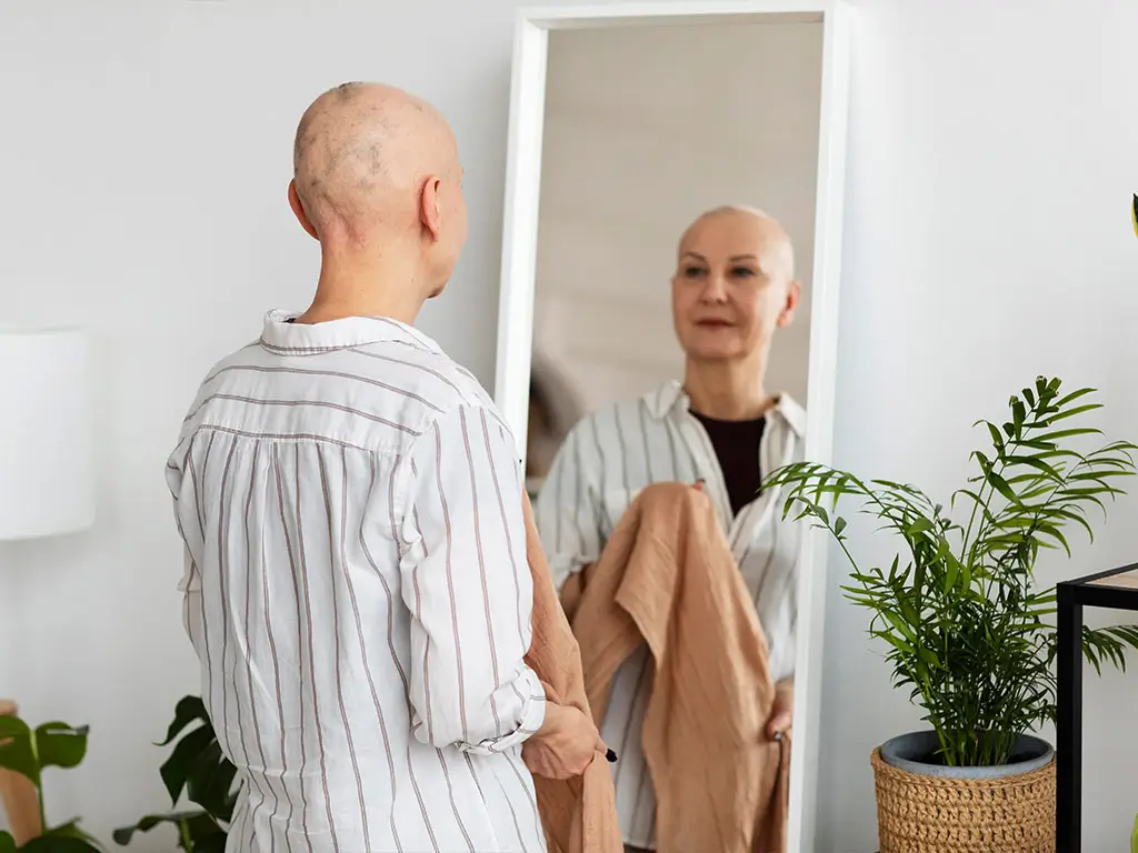 Cancer survivor looking in the mirror during life after cancer treatment